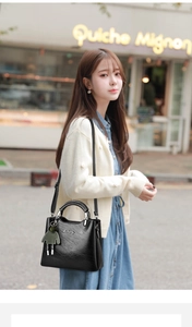 Detail view of black lychee-textured leather bag with silver rings and charm