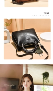 Detail of black oil wax leather handbag with metal ring handle and adjustable shoulder strap