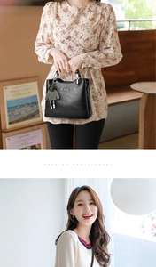 Detail of black leather handbag featuring silver logo and a cute doll charm accessory