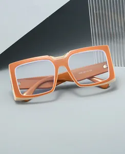 Close-up of retro square glasses with orange and beige contrast frames and metal hinges