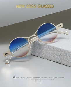 Detail of retro oval gold metal frames with blue gradient lenses on a textured stone