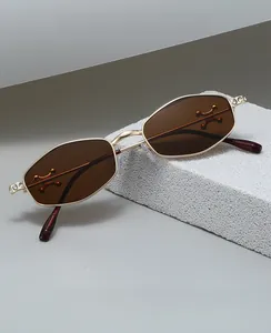 Detail of gold metal oval frame with crystal-encrusted hinges and dark brown lenses