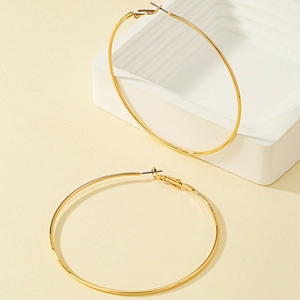 Minimalist large gold hoop earrings with polished finish on a clean geometric background