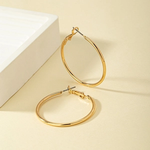 Dettaglio di grandi orecchini a cerchio in oro lucido su espositore in pietra beige