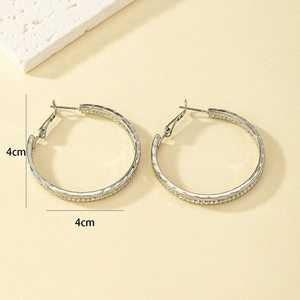 Détail des boucles d'oreilles créoles argentées texturées de 4cm de diamètre en forme C
