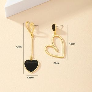 Détail de boucles d'oreilles cœur asymétriques en or avec émail noir et ajourage