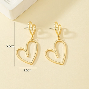 Détail de boucles d'oreilles cœur dorées mesurant 5,6 cm de long et 2,6 cm de large