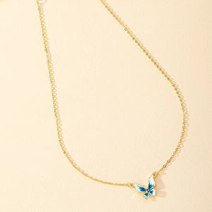 Elegant gold chain necklace featuring a gradient blue enamel butterfly pendant on beige background