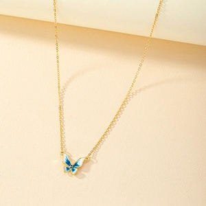 Golden chain necklace featuring a blue and white enamel butterfly pendant on a beige surface
