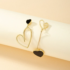 Vue macro de boucles d'oreilles cœur asymétriques plaquées or et émail noir