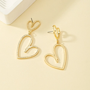 Gros plan détaillé de boucles d'oreilles pendantes coeur doré sur fond minimaliste