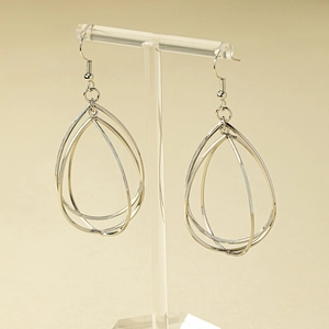 Three-layer hollow teardrop earrings in polished silver finish on a display stand