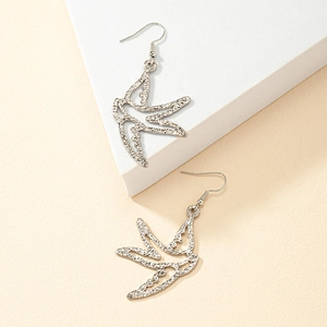Close-up of silver bird earrings with a hammered texture finish and minimalist design