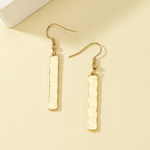Minimalist gold bar earrings with hammered texture and fish hook design in soft light