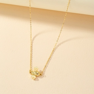 Elegant gold bee pendant necklace with minimalist chain in a soft natural light setting