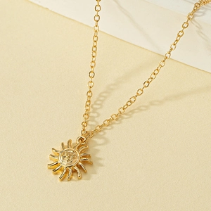 Detailed close-up of golden sun pendant with embossed face and fine cable chain