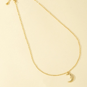 Detailed macro shot of vintage gold crescent moon face pendant on a delicate chain