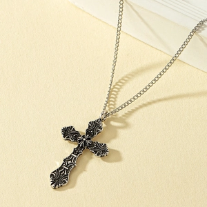 Detailed close-up of retro silver cross pendant with intricate baroque patterns and metal chain