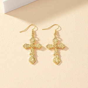 Close-up of gold cross earrings featuring intricate vintage European relief patterns