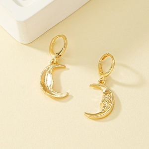 Élégantes boucles d'oreilles créoles lune dorées sur fond crème minimaliste
