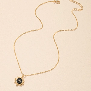 Golden sun medallion necklace with black enamel star center on a minimalist link chain