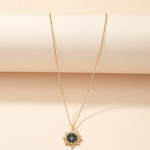 Elegant gold sunburst pendant necklace with black enamel center on a minimalist stand