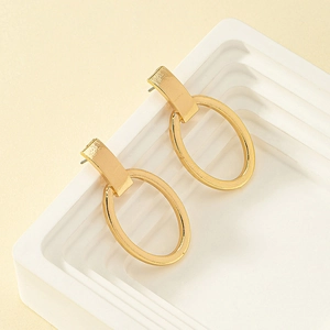 Detail shot of minimalist gold geometric hoop earrings on a white tiered display