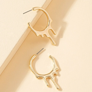 Gros plan de boucles d'oreilles créoles dorées avec design en métal fondu effet lave