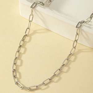 Polished silver paperclip chain necklace on geometric display stand with sleek metal finish