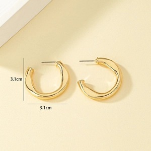 Golden chunky twisted C-shaped earrings with 3.1cm diameter on minimalist background