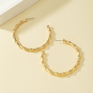 Detailed view of large gold hoop earrings with distinctive bamboo texture design