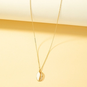 Minimalist gold chain necklace featuring a two-tone shell pendant on beige background