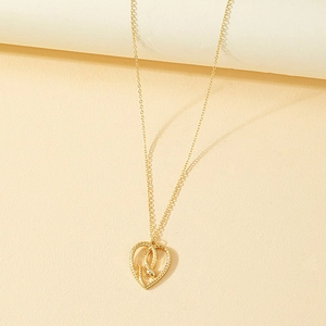 Exquisite gold-plated snake necklace with hollow heart-shaped pendant on beige surface