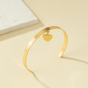 Minimalist gold heart charm open bangle bracelet with a polished metallic finish
