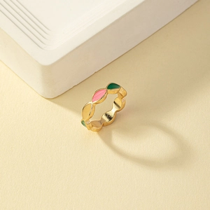 Detail of gold enamel ring featuring colorful marquise-shaped inlay on yellow surface