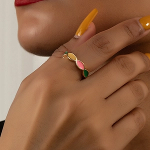 Detailed view of a gold-plated ring with colorful enamel oval patterns worn on a finger