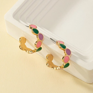 Macro shot of colorful enamel C-shaped gold earrings displayed on white stands