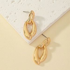 Close-up of interlocking twisted gold oval chain earrings on a textured stone surface