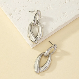 Polished silver chain earrings with interlocking oval rings on a textured white stone base