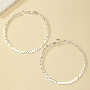 Minimalist silver braided hoop earrings with twisted texture shown on a beige background