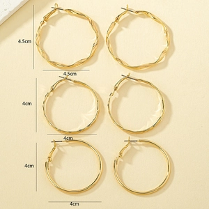 Three pairs of golden hoop earrings featuring twisted, wavy, and smooth metal textures