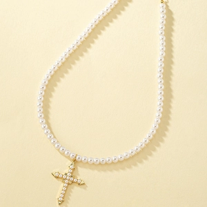 Elegant pearl necklace with a gold cross pendant on a textured beige background