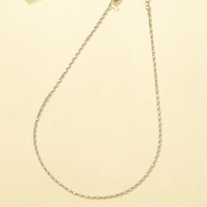 Minimalist silver chain necklace with adjustable link extension on yellow background