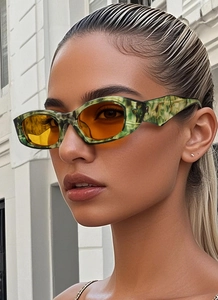 Gros plan de lunettes de soleil rétro avec monture marbrée verte et verres oranges