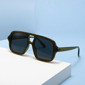 Olive green double-bridge pilot sunglasses on white geometric display with blue background
