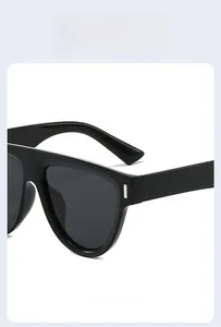 Détail de lunettes de soleil noires carrées montrant les accents argentés et la texture du cadre