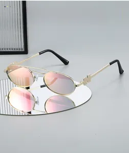 Detail of golden metal sunglasses frame with H-shaped logo and pink mirror lenses