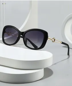 Close-up of square black sunglasses with hollow gold metal temples on a white pedestal