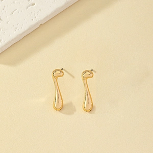 Macro detail of minimalist gold-plated musical note stud earrings with high-polish finish