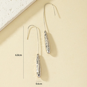 Macro shot of silver drop earrings with hammered texture and 6.8cm length detail